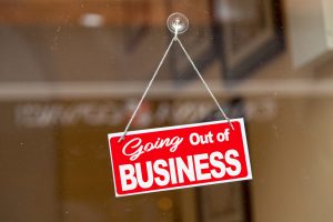 Red sign hanging at the glass door of a shop saying: "Going out of business".